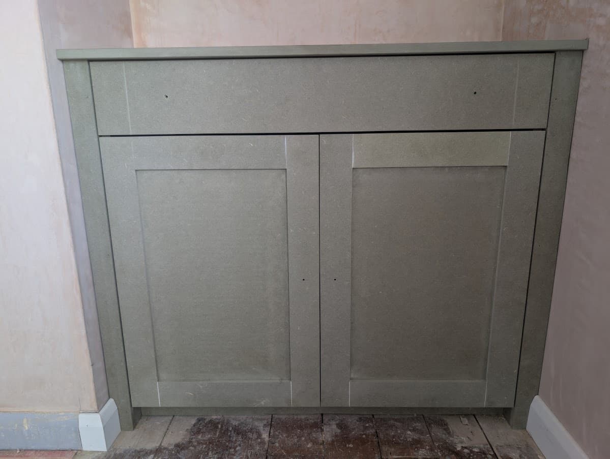 A built-in base cabinet with one drawer and two shaker-style doors, sprayed sage green