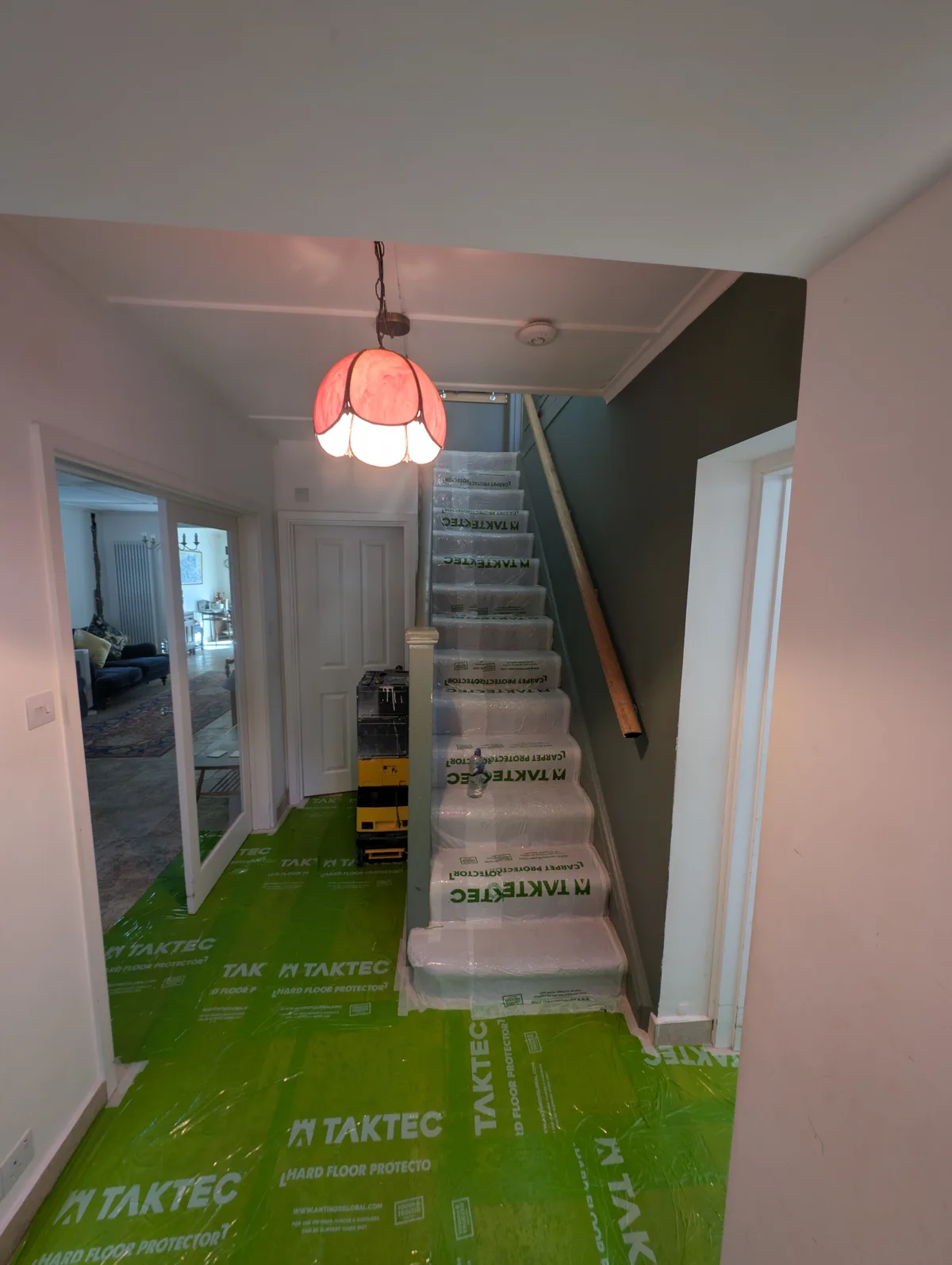 The same hallway before work: floors and stairs covered in protective sheeting, walls not yet finished