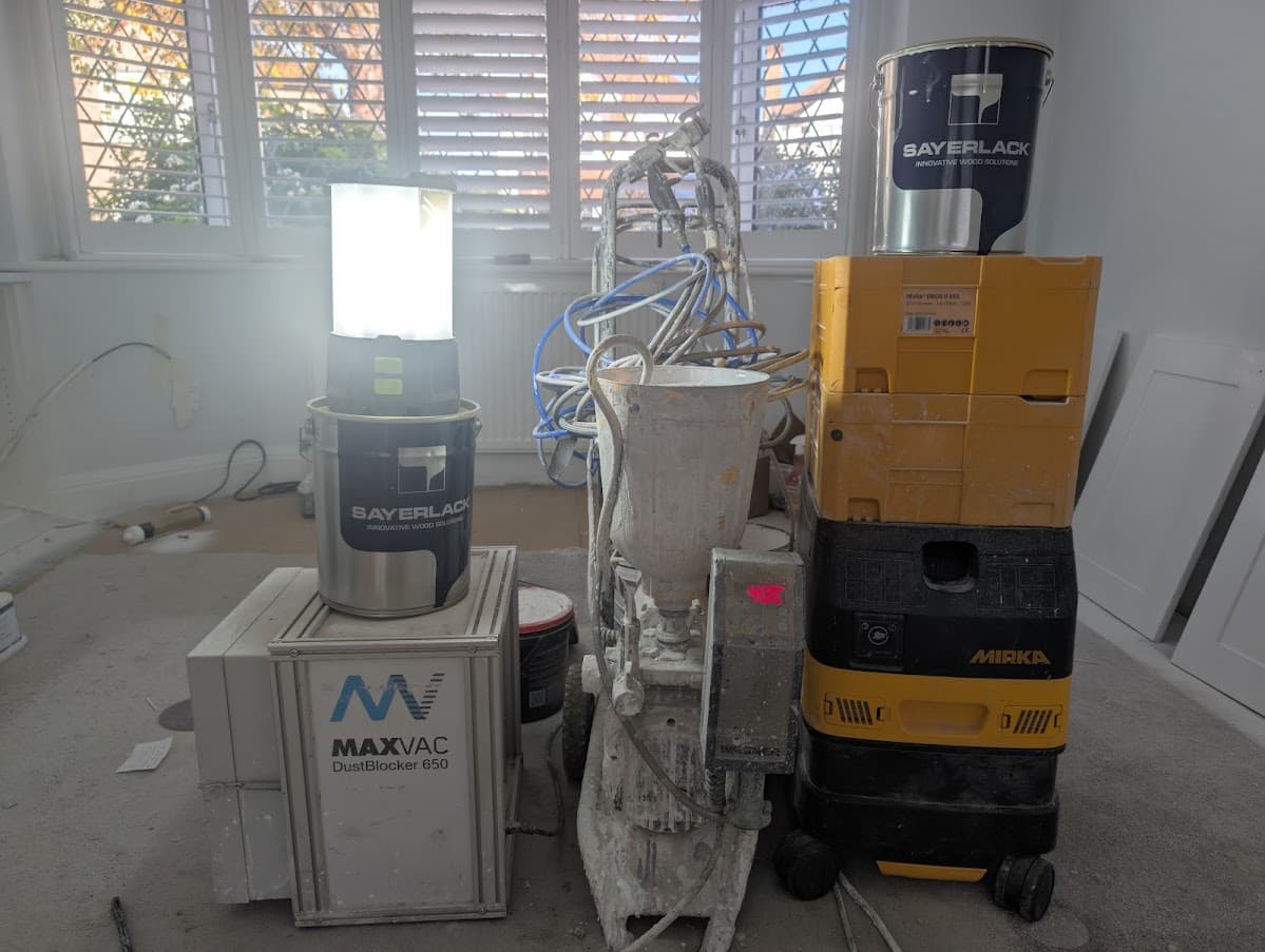 An airless spray rig and dust extraction unit set up in a room fitted with plantation shutters