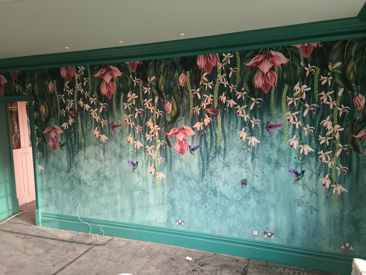 A teal tropical foliage mural wallpaper hung along a hallway wall, with matching teal paintwork on the surrounding trim