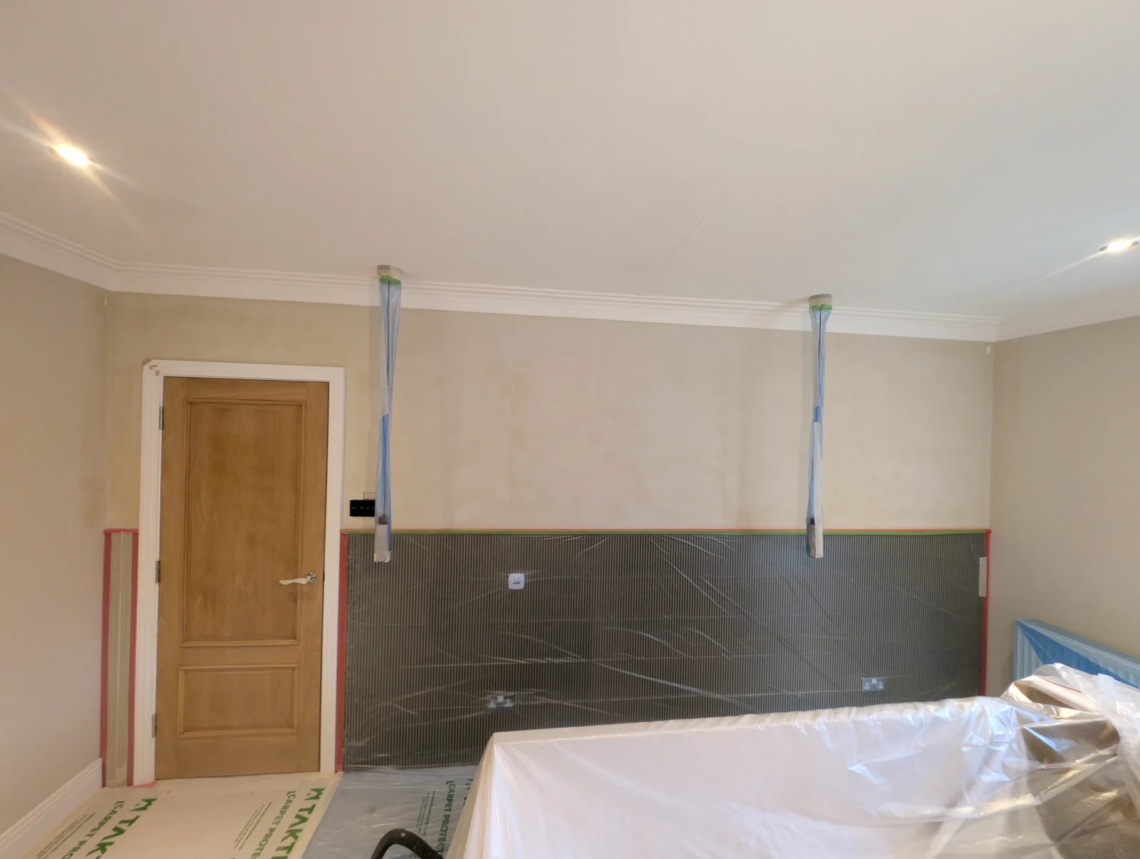 The same loft bedroom before work: walls in bare plaster, floors and doorways masked and protected ready for spraying