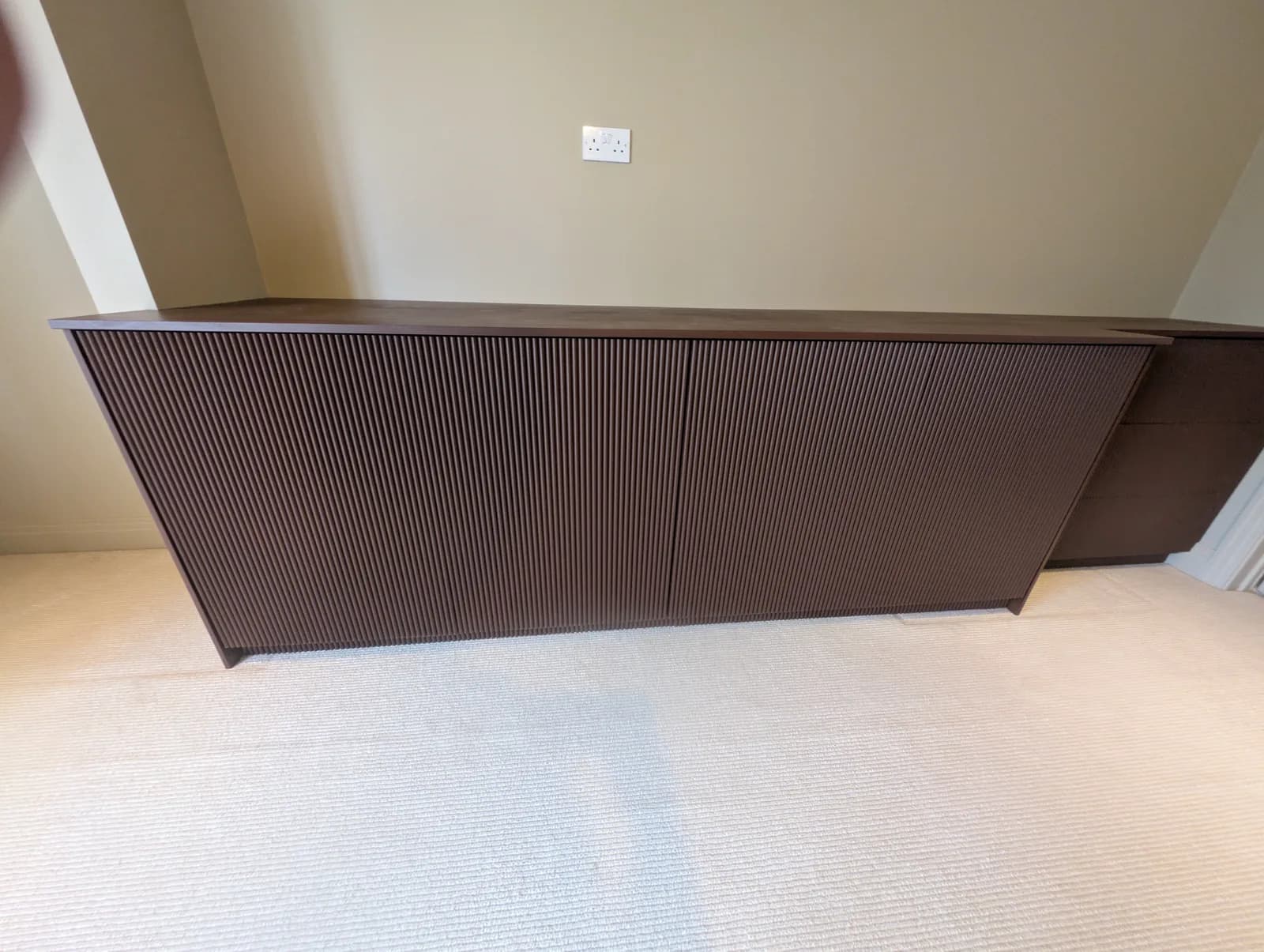 The bespoke fluted sideboard sprayed in a deep charcoal finish, positioned along the bedroom wall